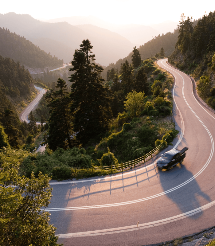 Pickup truck driving down winding mountainside road.